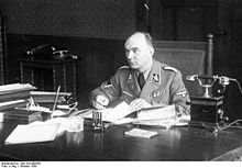 Photographie montrant Arthur Greiser assis à son bureau, en uniforme, sans couvre-chef