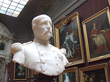 Buste en marbre blanc du duc, âgé, en tenue de militaire avec les tableaux de la grande galerie en arrière plan