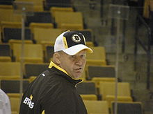 Photo de Claude Julien de 3/4 dos portant la casquette des Bruins.