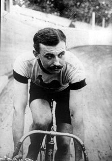 A man on a bicycle with shorts, short sleeves, racing on a velodrome.