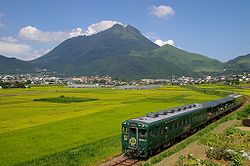 Vue du mont Yufu depuis le sud-ouest avec au premier plan le train quittant la ville de Yufuin.
