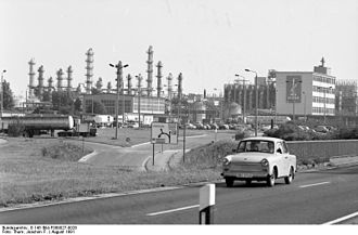 Photographie montrant une automobile en avant-plan, alors qu'à l'arrière apparaissent des installations industrielles.