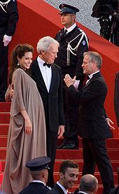 Angelina Jolie et Clint Eastwood, face au public, sur le tapis rouge, montant les marches du palais du Festival de Cannes, Gilles Jacob leur parlant