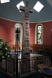 La haute croix est située dans une chapelle de l’église de Ruthwell, et bien qu’au fond d’une fosse, elle touche presque le plafond.