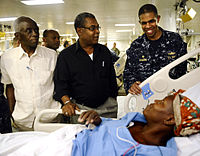 US Navy 100206-N-5345W-130 Capt. Sam Howard, commanding officer of the amphibious assault ship USS Bataan (LHD 5), right, visits Haitian patients in the medical ward with Haitian Prime Minister Jean-Max Bellerive.jpg