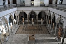 Salle de Carthage vue du deuxième étage avec les statues romaines et une mosaïque, ainsi que les arcades du palais.
