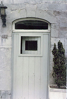 Une porte avec une petite fenêtre s'ouvrant dedans et une vitre fixe au-dessus