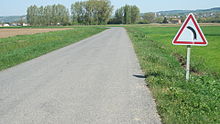 Route avec panneau annonçant un virage à gauche