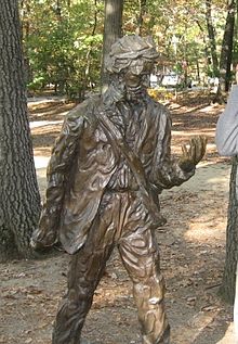 Statue à la mémoire de Henry David Thoreau près de sa cabane de Walden Pond. L'écrivain est représenté en marchant et en train de regarder sa main gauche. Il porte un sac en bandouillère.