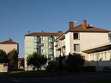 Photographie de logement HLM : au premier plan, un immeuble de trois étages rose clair et derrière, un immeuble de cinq étages vert pâle.