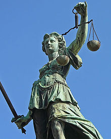 Statue représentant la Justice portant à main droite le glaive et à main gauche, bras en l'air, la balance.